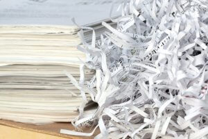 stack of files with shredded paper bits beside it